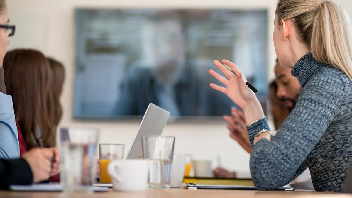 mulher apresentando trabalhos em uma tv para uma empresa em uma sala de reunião